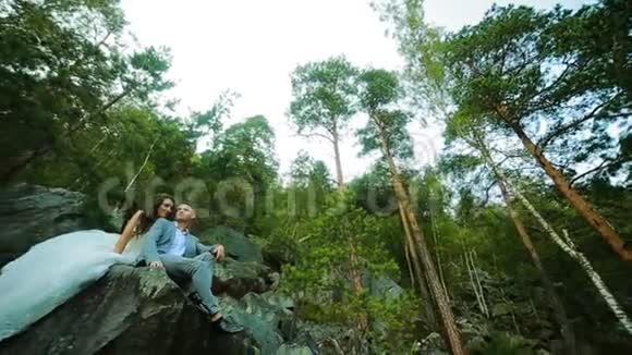 活跃的一对夫妇在森林里的岩石上爬着悬崖松树视频的预览图