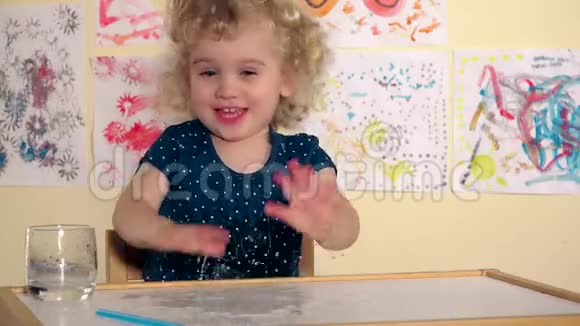 淘气的小女孩把水溅在桌子上兴奋的湿女孩积极情绪视频的预览图