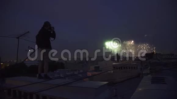 站在楼顶的年轻人在镜头前拍摄烟花视频的预览图