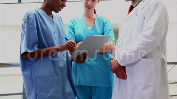 微笑的医生听护士拿着剪贴板视频的预览图