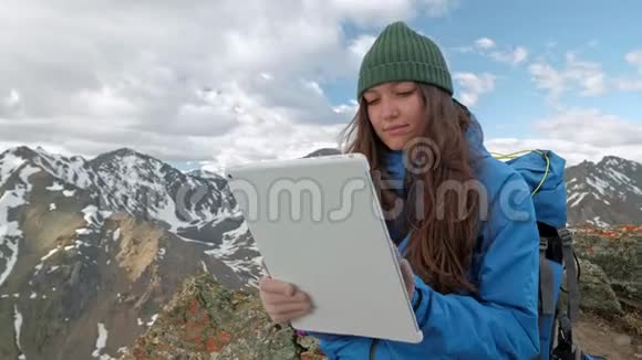 旅游女性自由职业者在自然界中使用电脑坐在煤气火炬旁边的草地上山区反映在视频的预览图