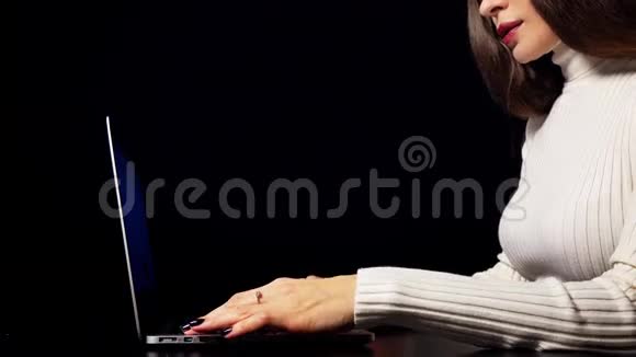 漂亮的黑发女人打字和使用她的笔记本电脑的轨迹板孤立于黑色背景下4K视频视频的预览图