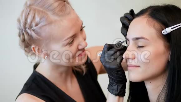 美容院戴着黑色橡胶手套的化妆师拿着镊子拔出眉毛师父纠正形状视频的预览图