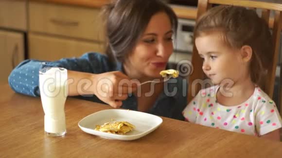一个小女孩吃炒鸡蛋妈妈用叉子喂她两个女孩都很开心视频的预览图