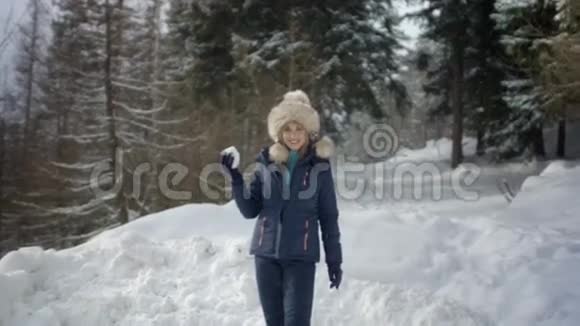 穿着冬装的漂亮女孩向照相机扔雪球视频的预览图