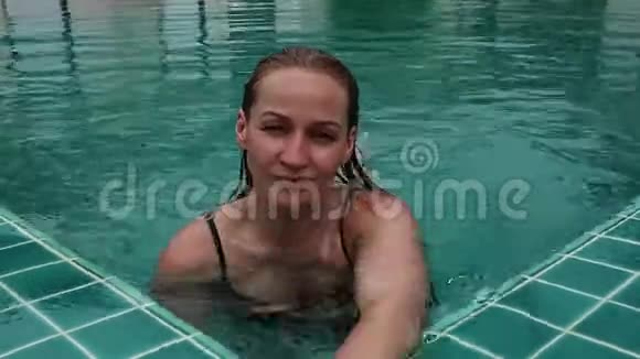 美丽快乐的苗条女人穿着黑色比基尼微笑着在酒店游泳池放松视频的预览图