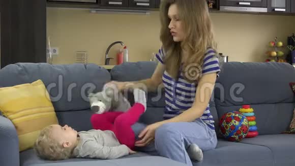 年轻快乐的妈妈带着玩具在沙发上和玩玩具4K视频的预览图