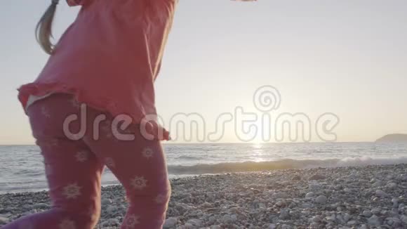 小女孩跑到海滩上迎接太阳高兴地跳起来视频的预览图
