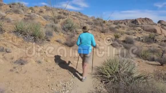 成熟活跃的女性在莫哈韦沙漠漫步小径后景4K视频的预览图