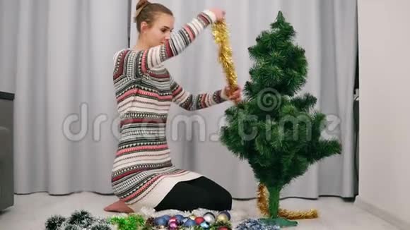 漂亮的幸福女人坐在人造圣诞树旁在家里装饰它视频的预览图