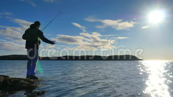 渔夫检查鱼线把鱼饵推到鱼竿上做好准备把鱼饵远远抛到平静的水里大人视频的预览图