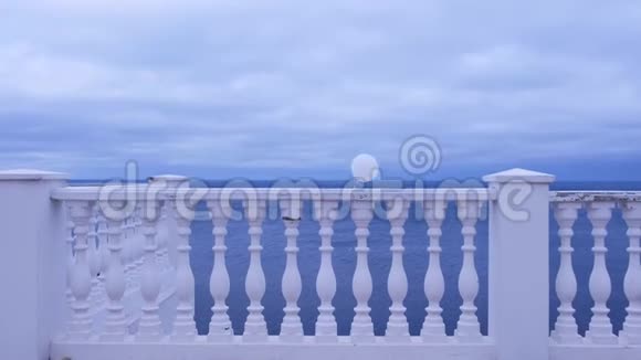 在一个阴郁的日子里白色的气球在风中系在海边的栅栏上视频的预览图