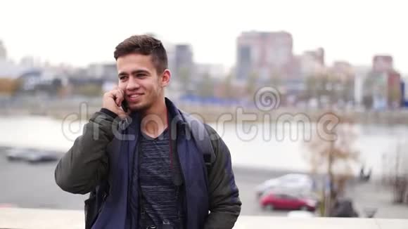 年轻时尚的男人在电话里讲话在城市慢动作中微笑视频的预览图