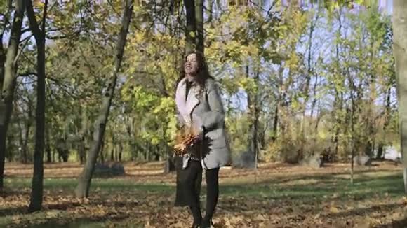 年轻女子在秋天公园扔黄叶视频的预览图