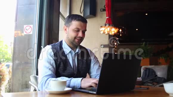 自由职业者商人在咖啡馆里做笔记本电脑和喝咖啡追踪和曝光镜头视频的预览图