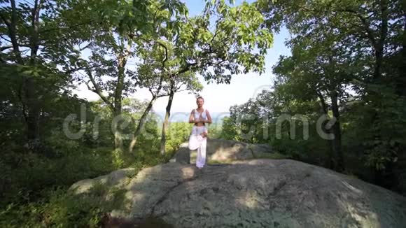 年轻女子正在一座山顶上美丽的异国情调的地方练习瑜伽瑜伽和冥想视频的预览图