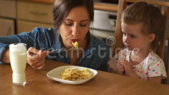 一个美丽的黑发正在喂养她的女儿她吹着食物给那个女孩婴儿食品健康食欲A视频的预览图