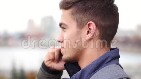 年轻时尚的男人在电话里讲话在城市慢动作中微笑视频的预览图