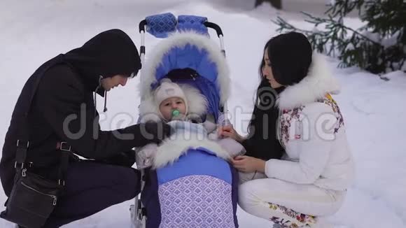 幸福的已婚夫妇毛毯使他的孩子挺直只是坐在轮椅上手里拿着奶嘴视频的预览图