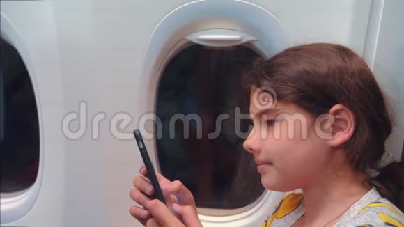 航空飞机概念年轻女孩正坐飞机在窗户旁边聊天生活方式在看着视频的预览图