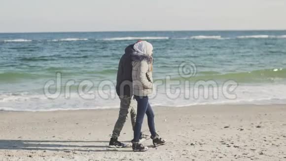 年轻人和女人在海滩上散步在寒冷的冬日一对夫妇在海上视频的预览图