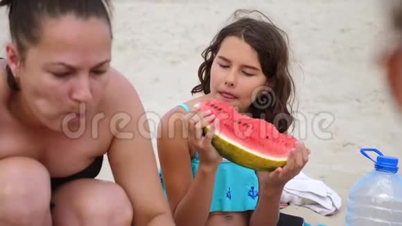 孩子们青少年在海滩上休息笑着吃西瓜慢动作视频少女生活方式青少年视频的预览图
