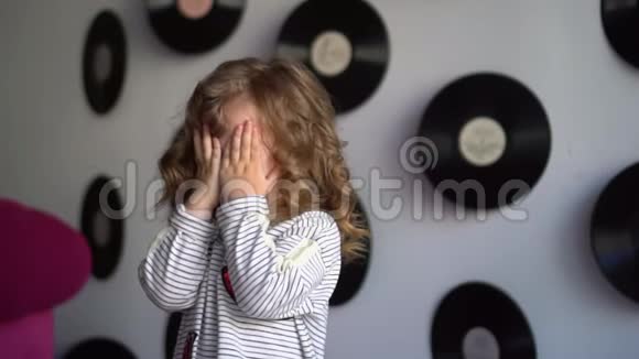 小可爱的女孩面对着摄影棚里的摄像机这个金发女孩花在蓝色背景上美丽的小女孩视频的预览图