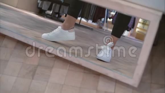 商店里一位年轻女子在镜子旁试穿白色运动鞋视频的预览图