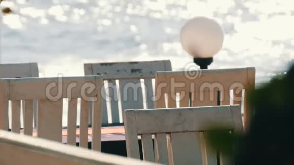 荒凉的咖啡馆海边有白色的木椅背景是海浪涌入阳光咖啡厅视频的预览图