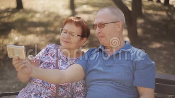 成熟的情侣坐在长椅公园里自拍视频的预览图