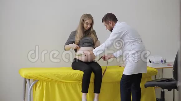 医生测量她的病人孕妇的腹部体积并在剪贴板上做笔记视频的预览图