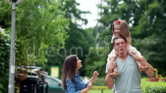 家人的吻妈妈爸爸和小女儿在城市公园里走来走去视频的预览图