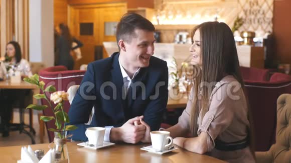 有魅力的年轻夫妇在餐馆里一边喝咖啡一边出去聊天视频的预览图