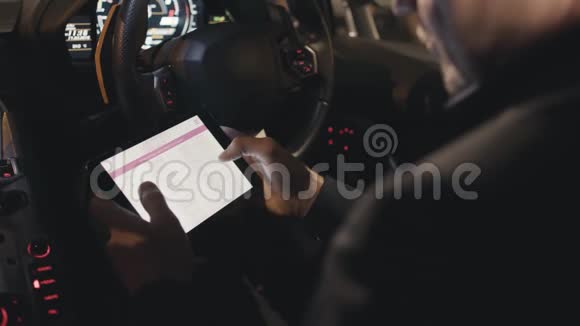 坐在车里的时候用数码平板电脑把手举起来库存商人检查平板电脑上的股票视频的预览图