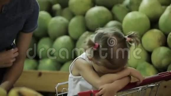 当妈妈在超市挑选水果时宝宝很累地坐在购物车里视频的预览图