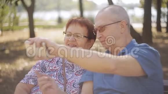成熟的情侣坐在长椅公园里自拍视频的预览图
