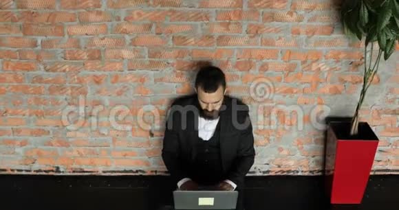 一个穿西装的男商人正在一个阁楼风格的现代办公室工作一个专心致志的人在项目上工作视频的预览图