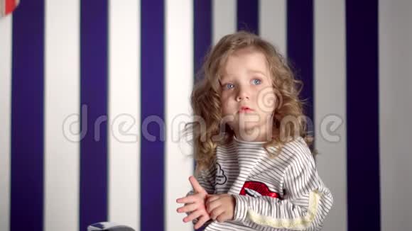 这个金发女孩花在蓝色背景上那个戴着戒指的漂亮小女孩在镜头前微笑视频的预览图