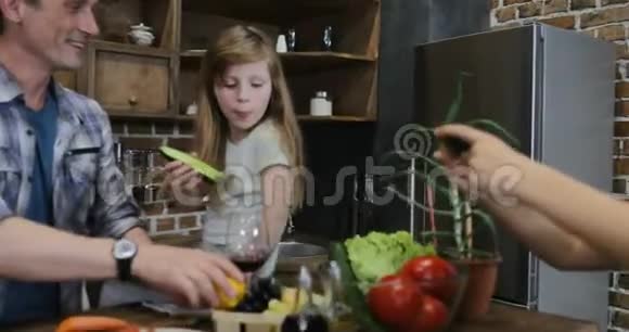 儿子拍摄的视频父母和姐姐在厨房用手机做饭幸福的家庭一起在家准备视频的预览图