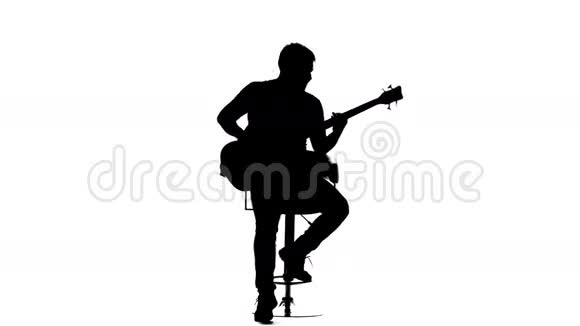 男人坐在椅子上演奏低音吉他剪影视频的预览图