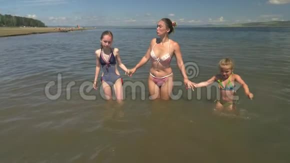 妈妈和她的孩子们正跑进水里视频的预览图