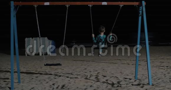 孤独的孩子晚上在海滩上荡秋千视频的预览图