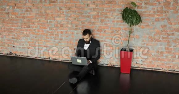 以阁楼风格在内政部工作的人时髦的时髦男人在砖墙背景下工作他就是视频的预览图