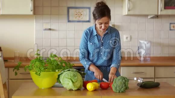 一个可爱的女孩正在厨房做饭她切蔬菜跳音乐心情很好素食视频的预览图