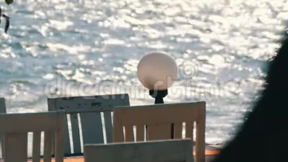 荒凉的咖啡馆海边有白色的木椅背景是海浪涌入阳光咖啡厅视频的预览图