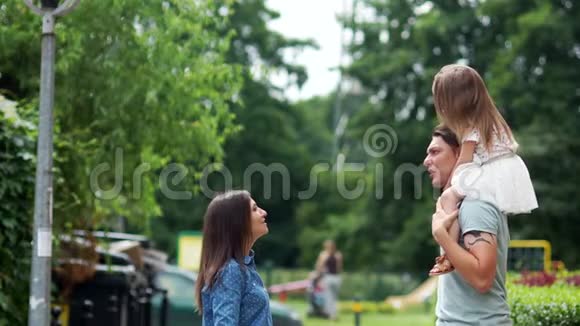 一个幸福的年轻家庭妈妈爸爸和小女儿在公园里玩得很开心周末家庭假日视频的预览图