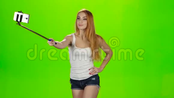 红头发的女孩用自拍棒制作各种照片绿色屏幕视频的预览图
