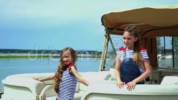 那个动作慢下来的小美丽的女孩在水上的小船附近转过身来两个姐妹视频的预览图