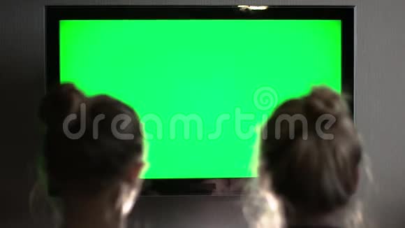 两个年轻的金发金发金发碧眼的看着绿色的电视屏幕他们的头互相倾斜视频的预览图