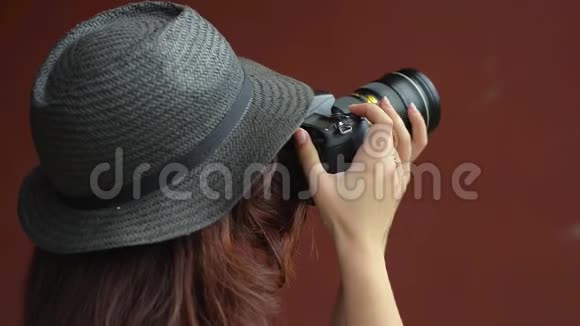 一个戴帽子的女孩用单反相机拍摄照片特写镜头视频的预览图